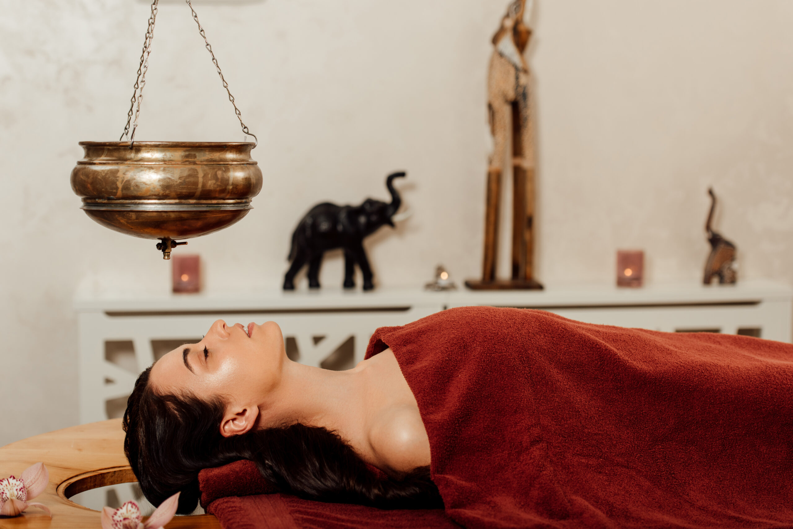 side view of woman lying under shirodhara vessel during ayurvedia